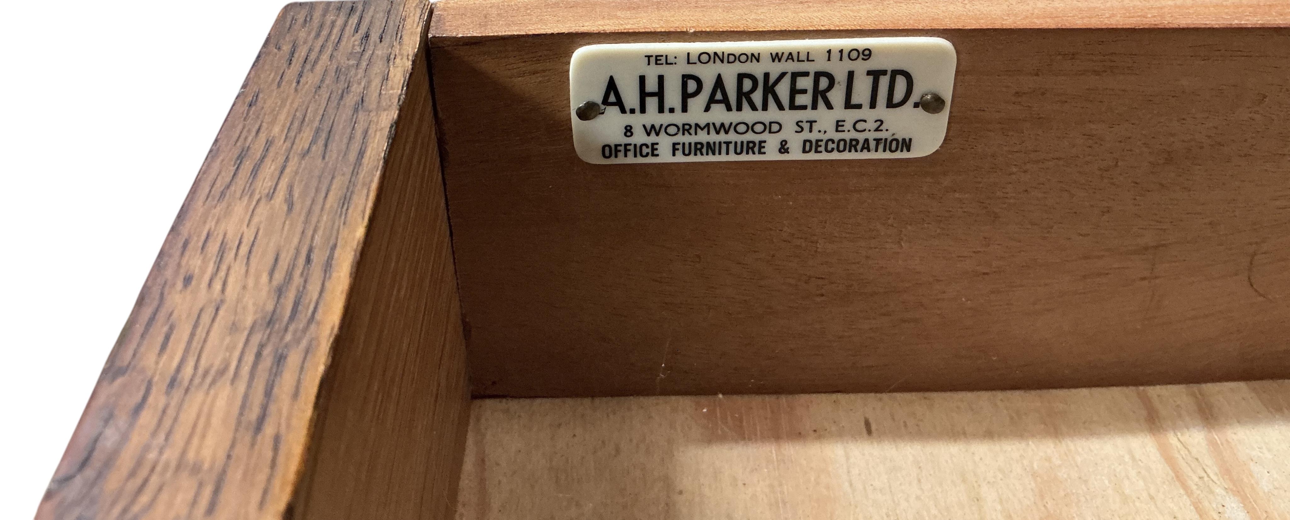 A 1920's oak two drawer writing table, A H Parker retailers, width 122cm, depth 69cm, height 77cm